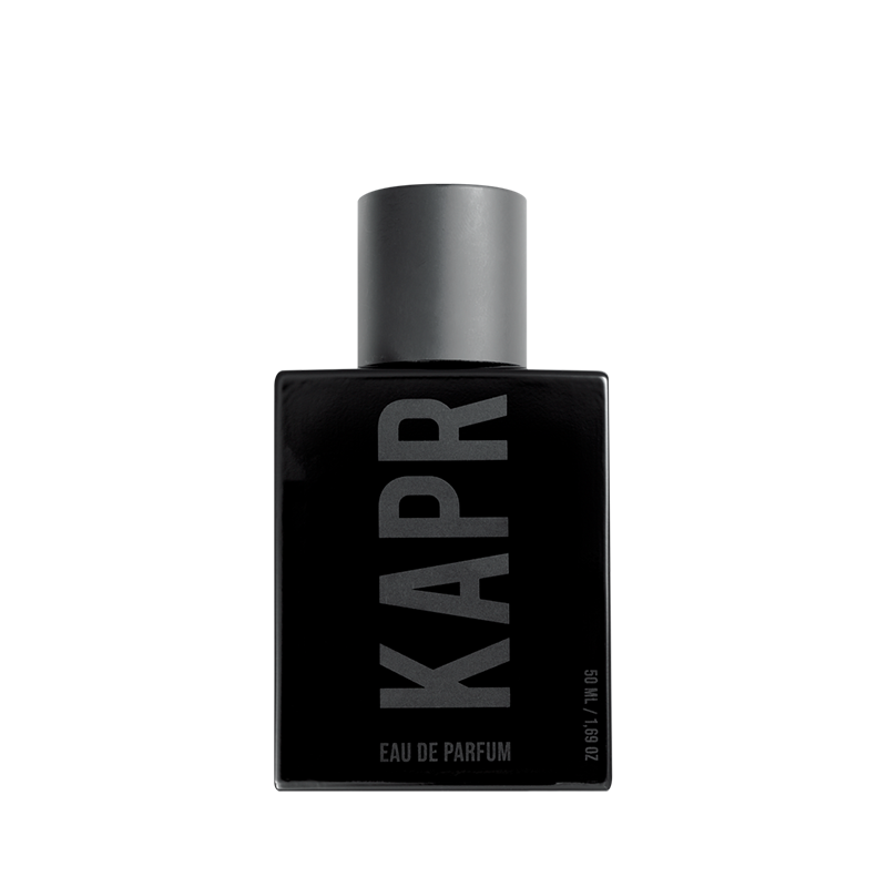 Mannelijk model met een stoere uitstraling gebruikt KAPR product.|KAPR exclusive Geur 50ml - Belangrijkste Geurkenmerken|KAPR Luxe Geur 2ml flesje met de tekst 'Eau de Essence'.|KAPR Luxe Parfum 50ml Fles en Doos - Eau de Parfum