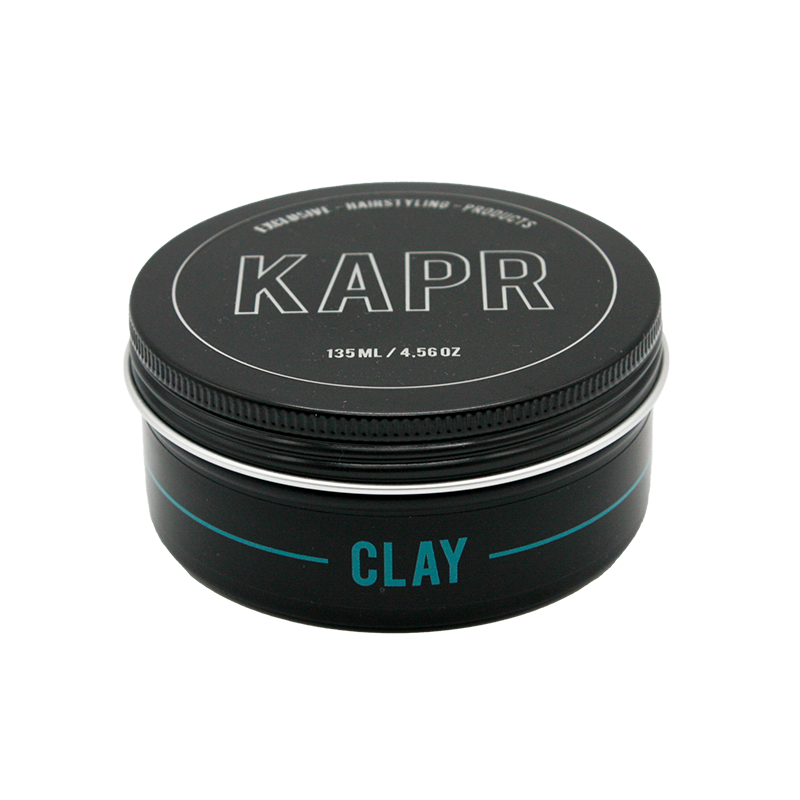 model met een strakke en matte look.|KAPR haarklei- Luxe zwarte kleiverpakking tegen een stijlvolle donkere achtergrond.||KAPR Clay 60ml met eigenschappen zoals extreme hold en verfrissende geur.