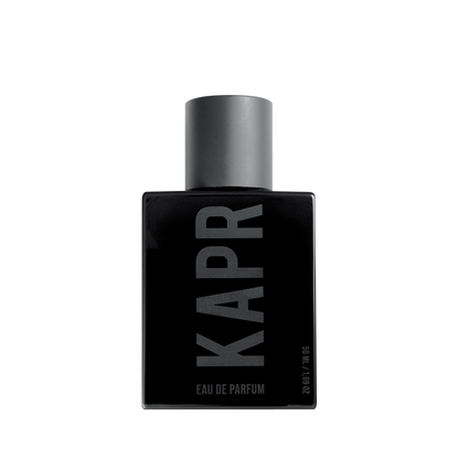 Mannelijk model met een stoere uitstraling gebruikt KAPR product.|KAPR exclusive Geur 50ml - Belangrijkste Geurkenmerken|KAPR Luxe Geur 2ml flesje met de tekst 'Eau de Essence'.|KAPR Luxe Parfum 50ml Fles en Doos - Eau de Parfum