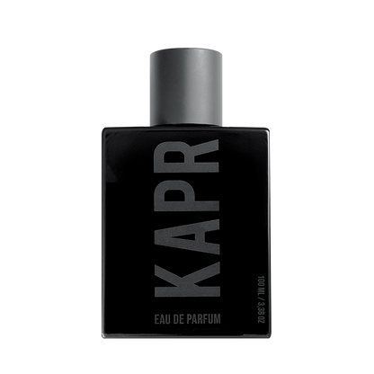 Mannelijk model met een stoere uitstraling gebruikt KAPR product.|KAPR exclusive Geur 50ml - Belangrijkste Geurkenmerken|KAPR Luxe Geur 2ml flesje met de tekst 'Eau de Essence'.|KAPR Luxe Parfum 50ml Fles en Doos - Eau de Parfum