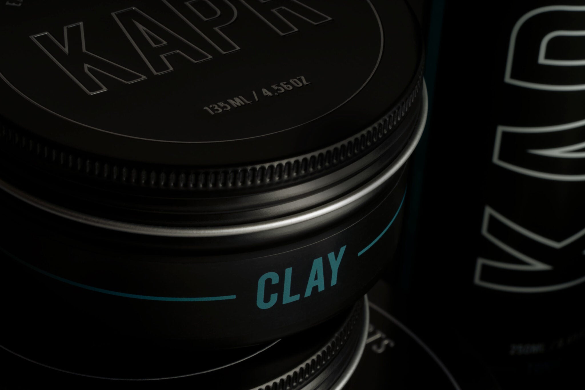 Close-up van KAPR Clay – zwarte pot met blauwe tekst en subtiele glans, premium hairstyling clay.