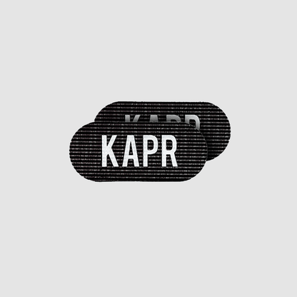 KAPR Grippers – zwarte haargrip met wit logo op grijze achtergrond, professioneel barbershop accessoire.