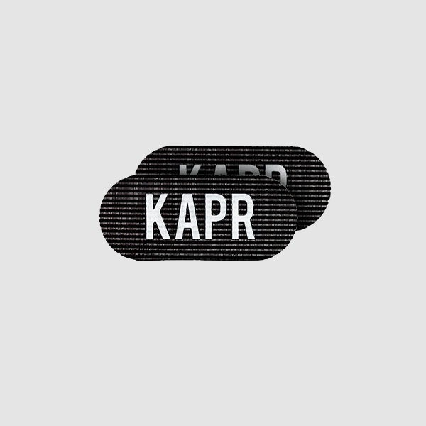 KAPR Grippers – zwarte haargrip met wit logo op grijze achtergrond, professioneel barbershop accessoire.