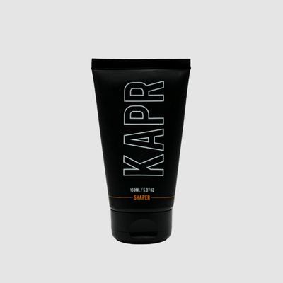 KAPR Shaper – zwarte tube met wit logo op grijze achtergrond, professionele barbershop styling.