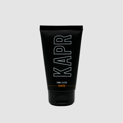 KAPR Shaper – zwarte tube met wit logo op grijze achtergrond, professionele barbershop styling.